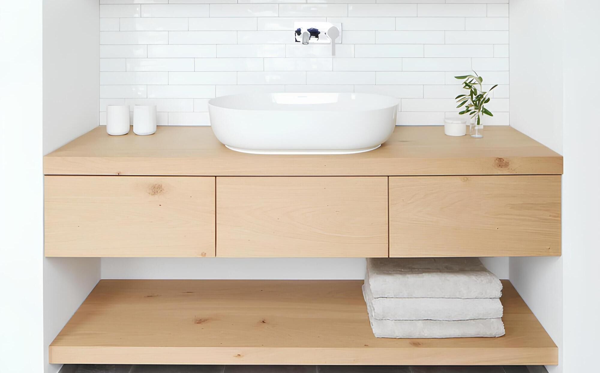 Das minimalistisch gestaltete Badezimmer besticht durch einen Waschtisch aus hellem Holz mit einem weißen Aufsatzwaschbecken
